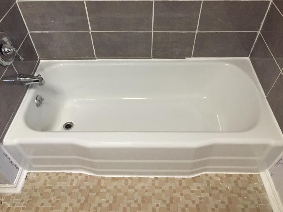A white bathtub is sitting in a bathroom next to a tiled wall.