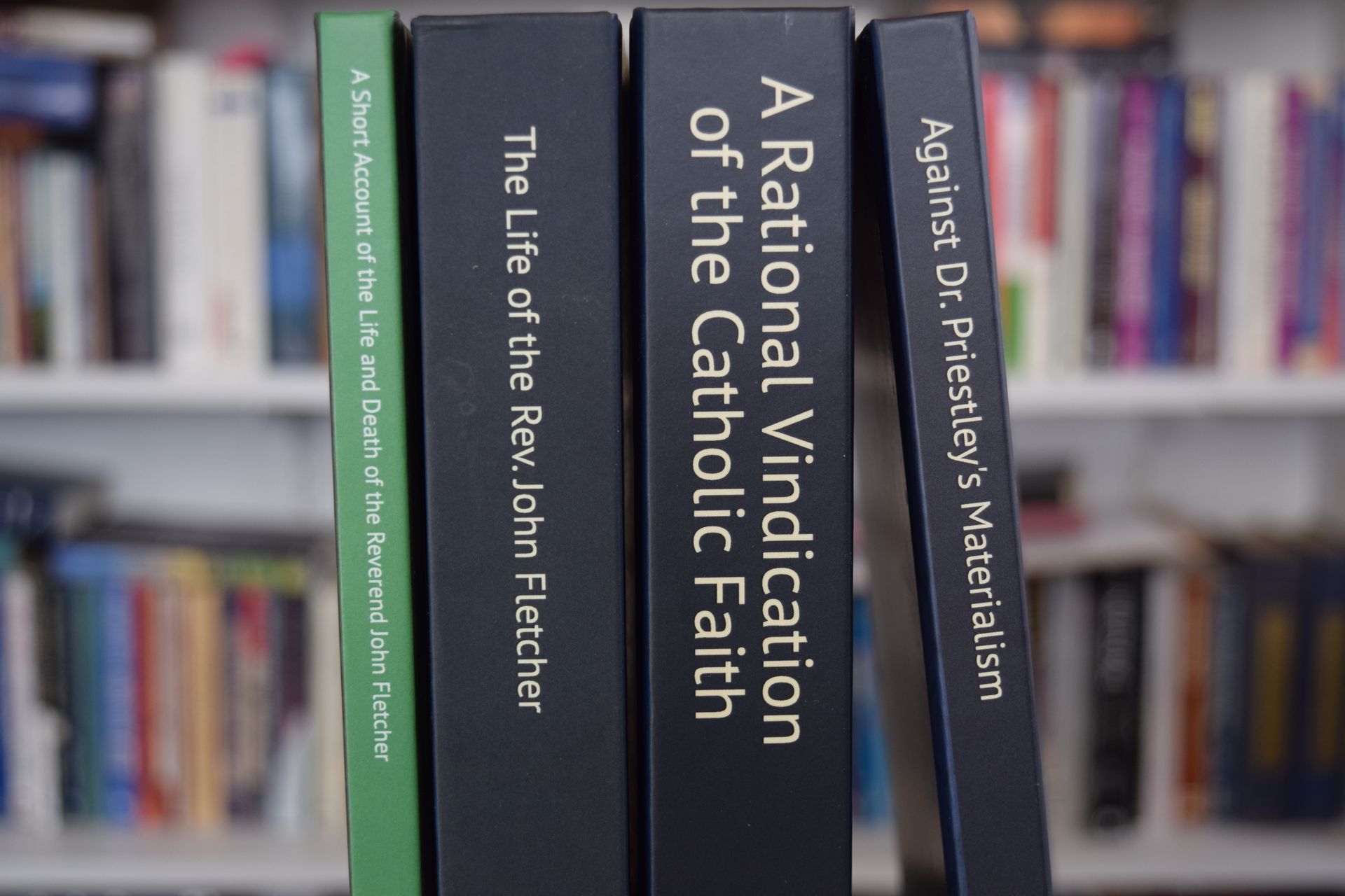 Four books stand vertically on a shelf, showing their spines with titles in white text against black and green covers.