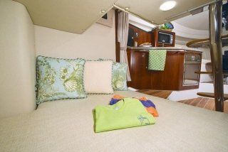 Un letto con cuscini e una camicia verde in una stanza su una barca.