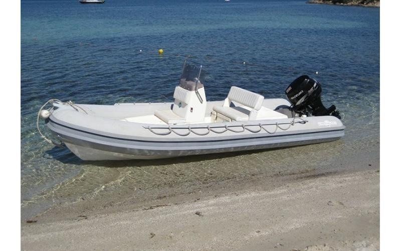 Una barca bianca con un motore Mercury è ormeggiata sulla spiaggia, vicino all'acqua.