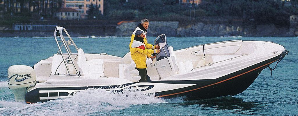 Un uomo con una giacca gialla sta guidando una barca in acqua