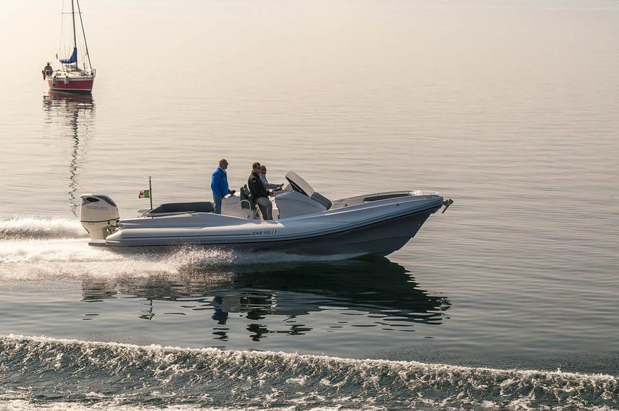 Una barca galleggia sulla superficie di uno specchio d'acqua con una barca a vela sullo sfondo.