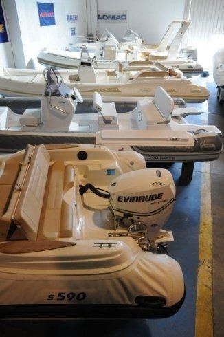 Una fila di barche bianche con motori Evinrude sono allineate in un magazzino.