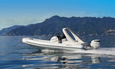 Una barca bianca galleggia sulla superficie di un lago con le montagne sullo sfondo.