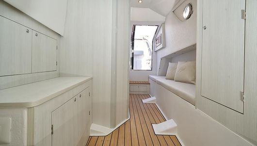 Un lungo corridoio con pavimento in legno e armadi bianchi