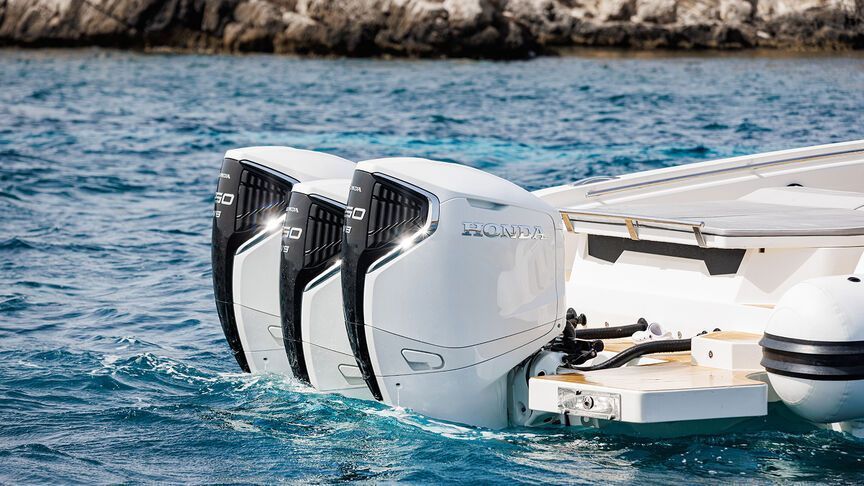 Una barca bianca con tre motori galleggia sulla superficie dell'acqua.