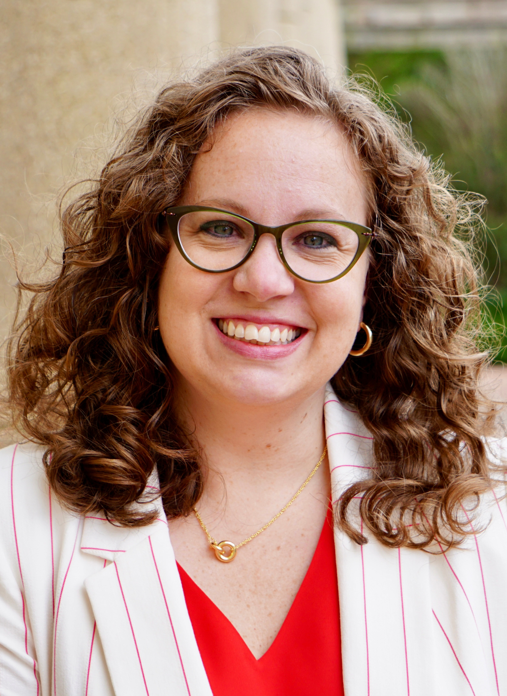 A White woman with brown curly hair and glasses