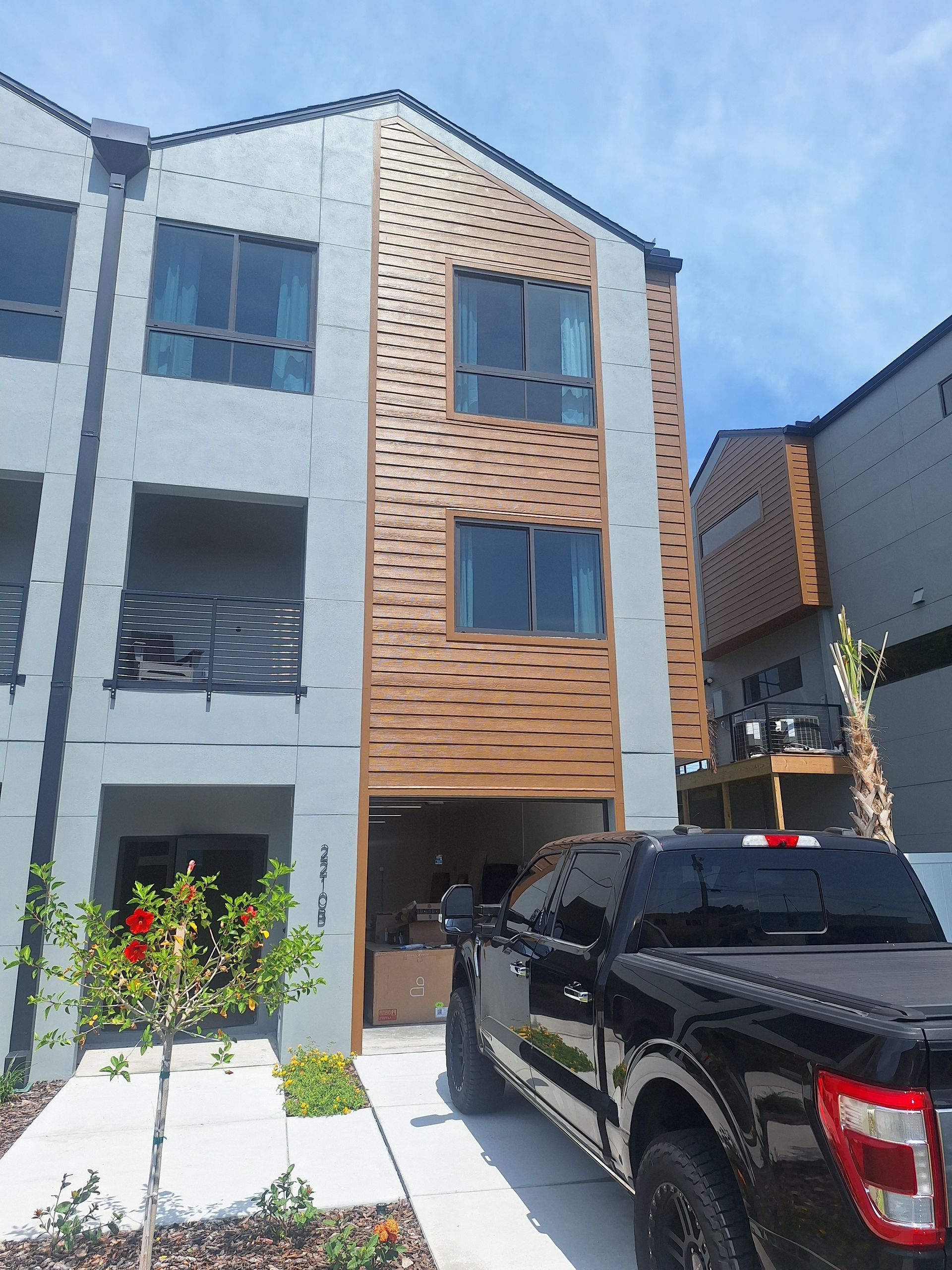 Modern townhome exterior with gray and wood siding, truck parked in front.