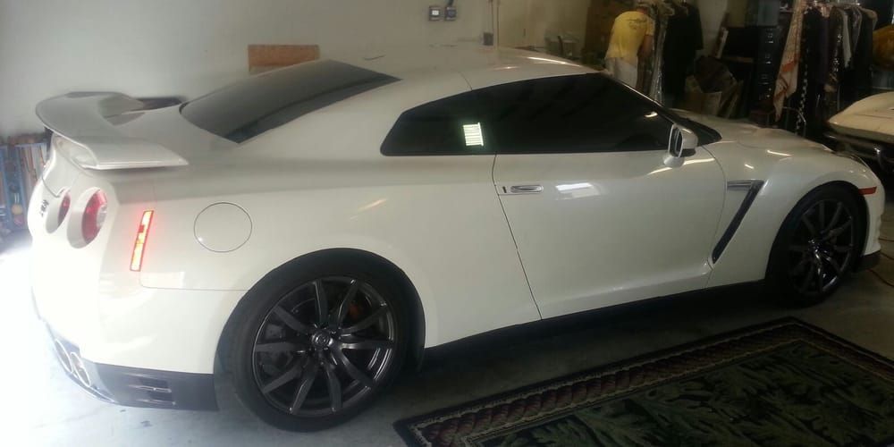 White Nissan GT-R sports car parked inside a garage, with dark tinted windows and black rims.
