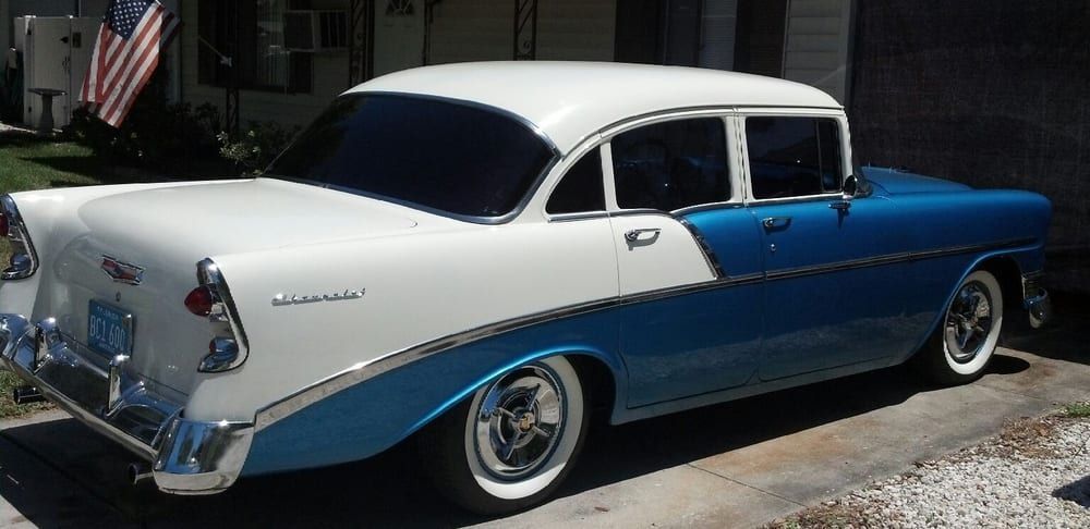 A two-tone white and blue 1956 Chevrolet Bel Air sedan with chrome trim and whitewall tires.