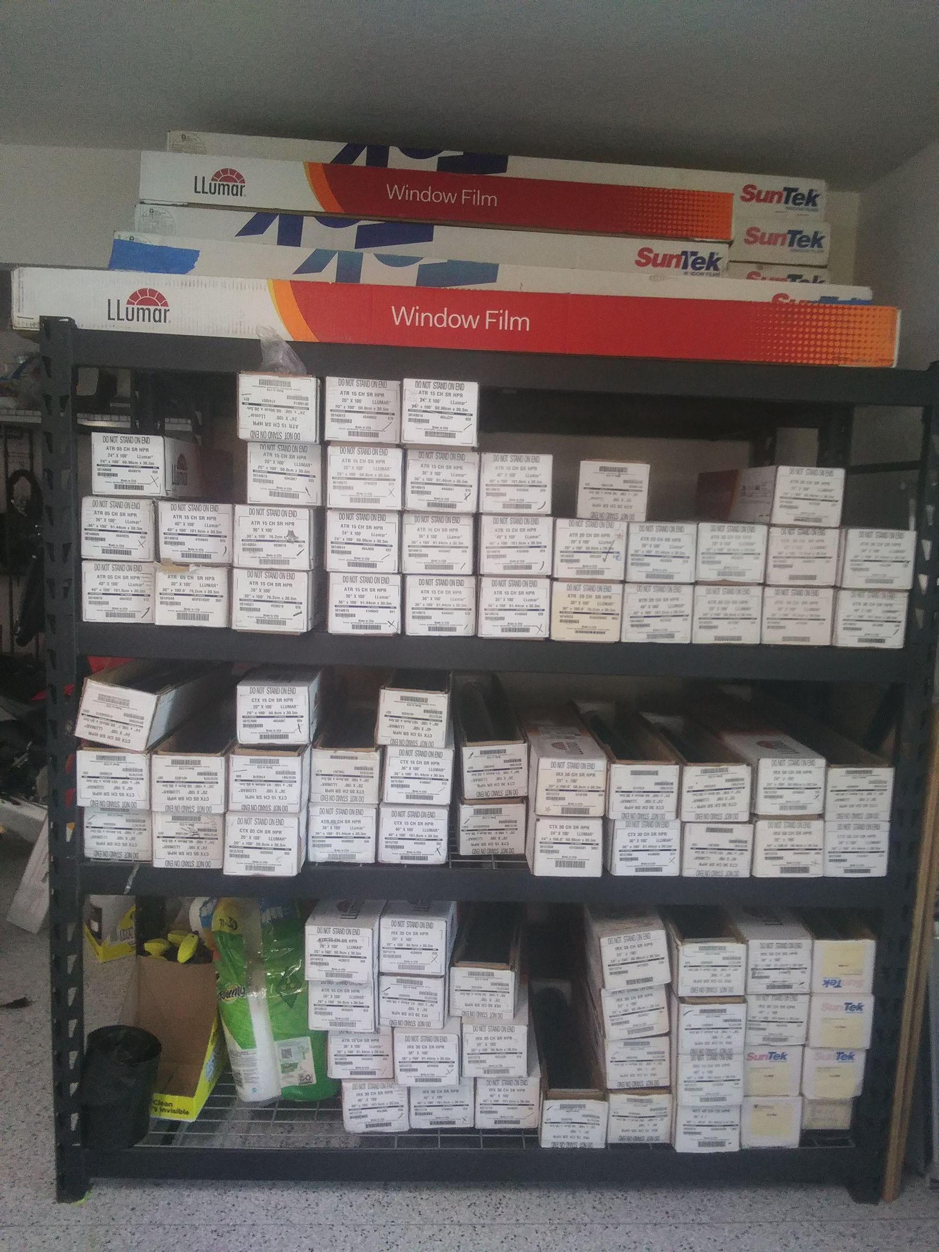 Black metal shelving unit holding many white boxes and long, rolled boxes.