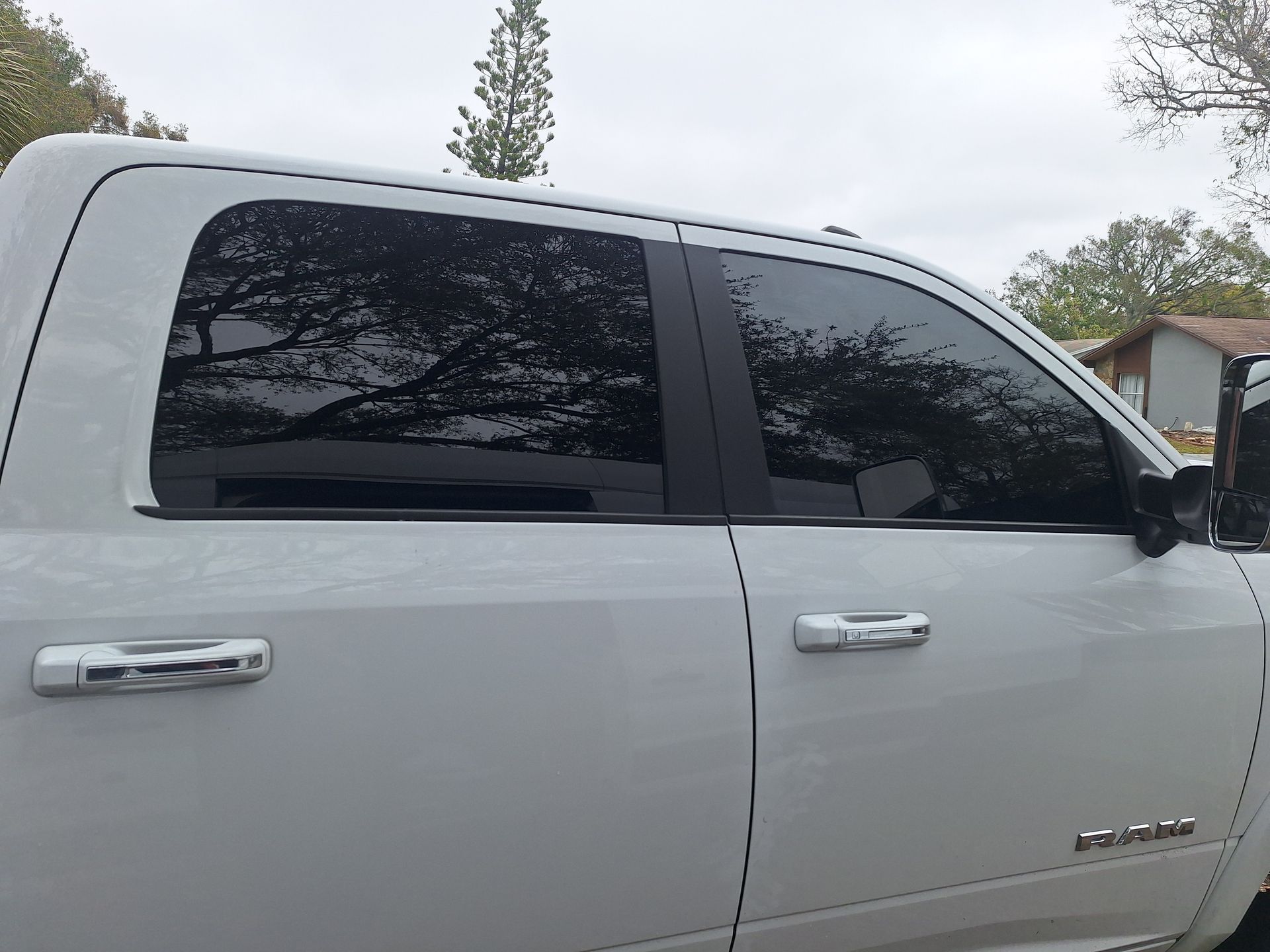 White pickup truck with tinted windows parked outside on a cloudy day.