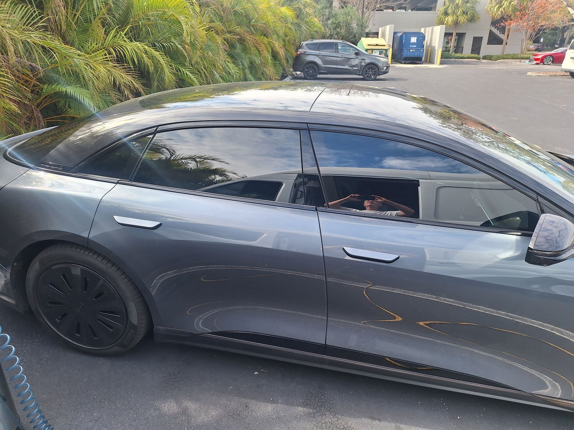 Gray Lucid Air sedan parked in a parking lot, tinted windows.
