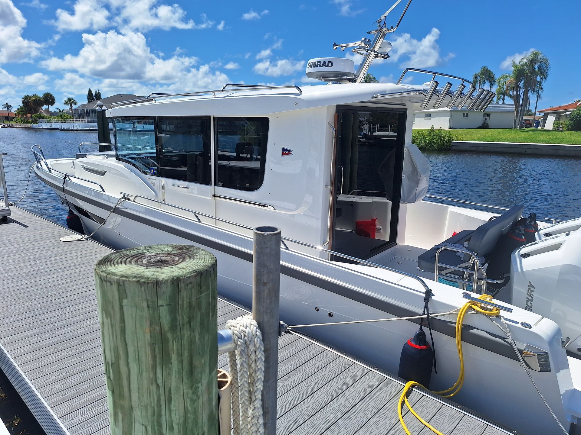 White motorboat docked at a wooden pier on a canal.