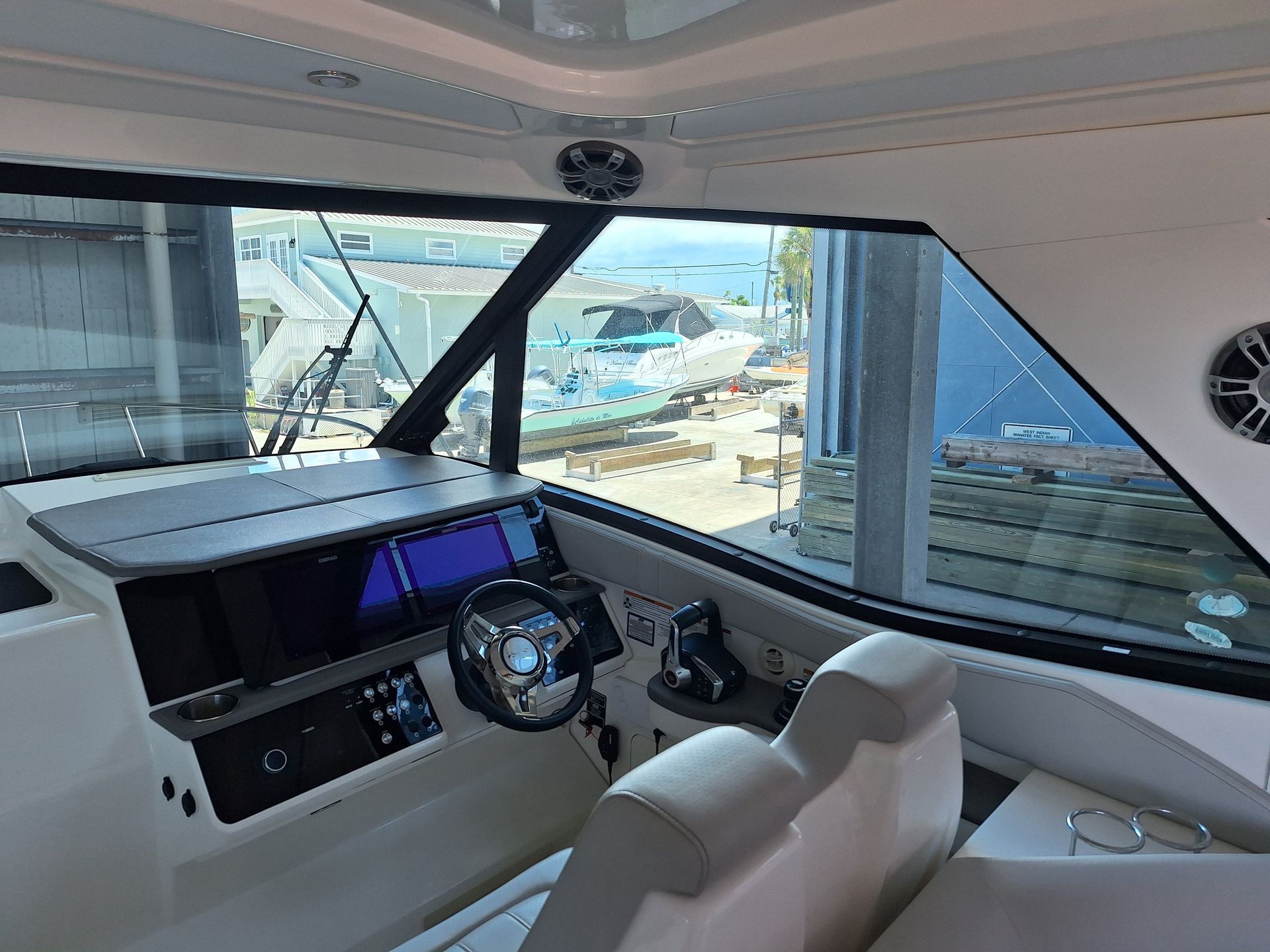 Boat cockpit interior with navigation screens, steering wheel, and exterior view.