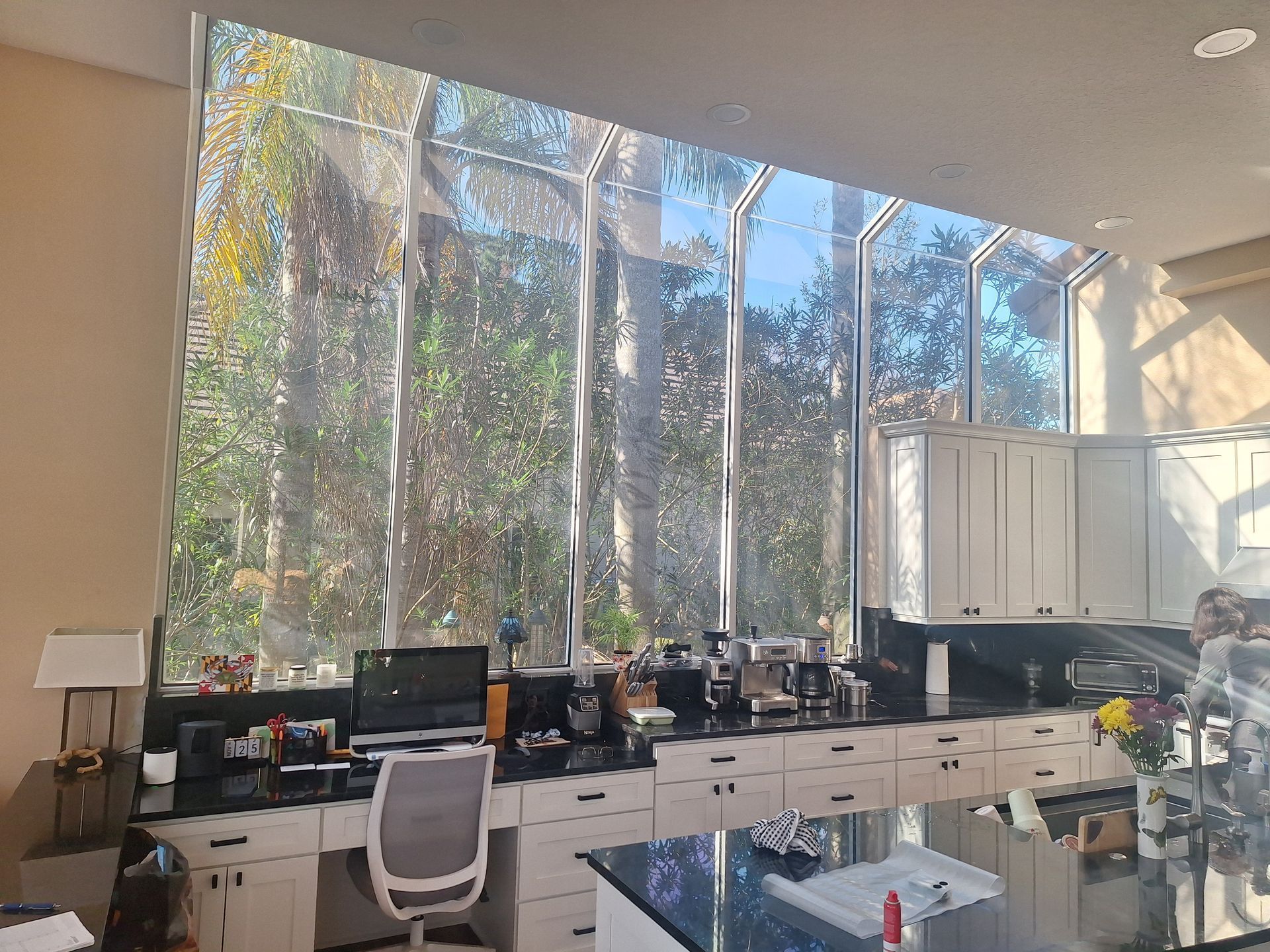 Kitchen with a large window overlooking trees, a desk, and cabinets with countertops.