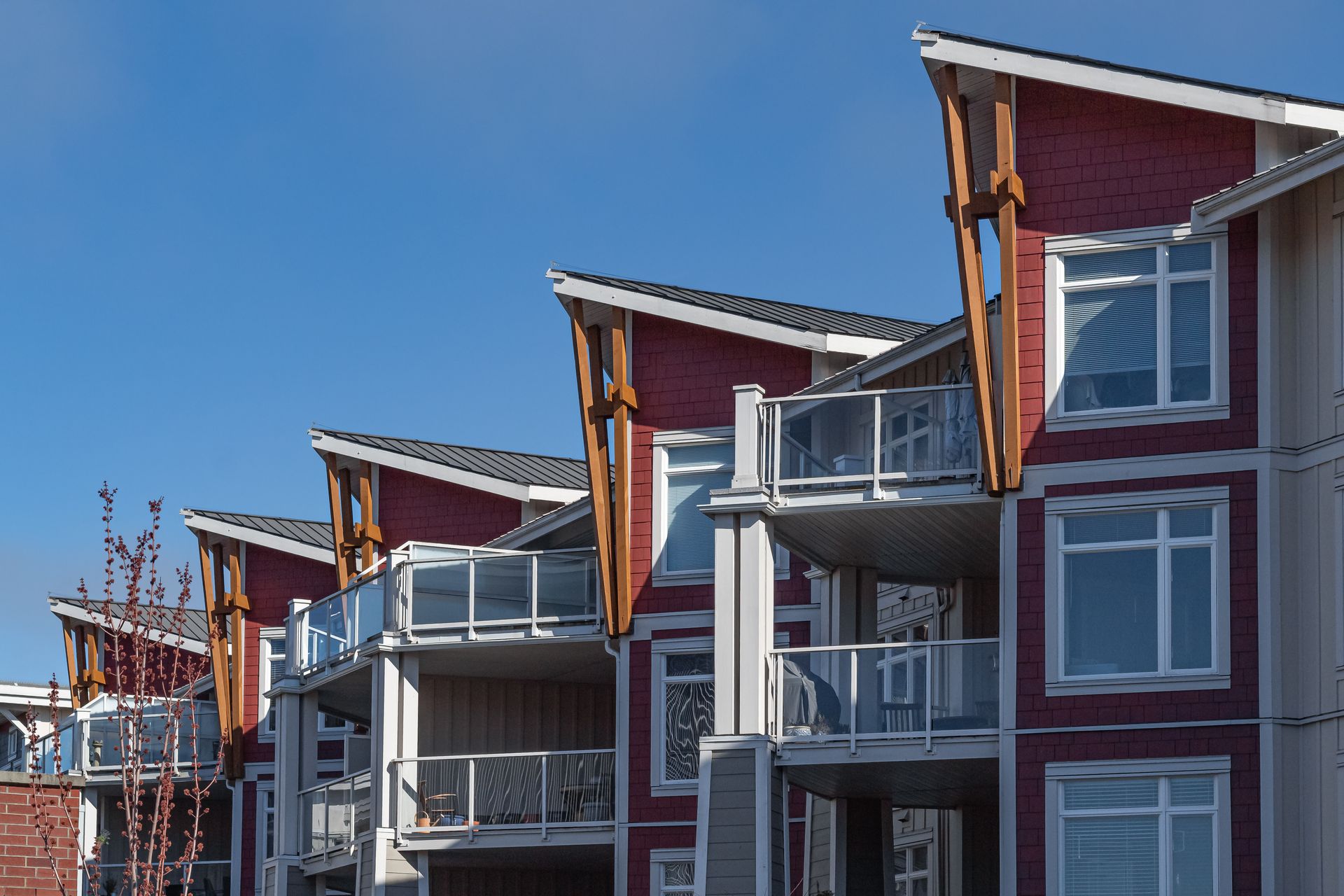 Immeuble d'appartements avec façade rouge et balcons se détachant sur un ciel bleu azur.