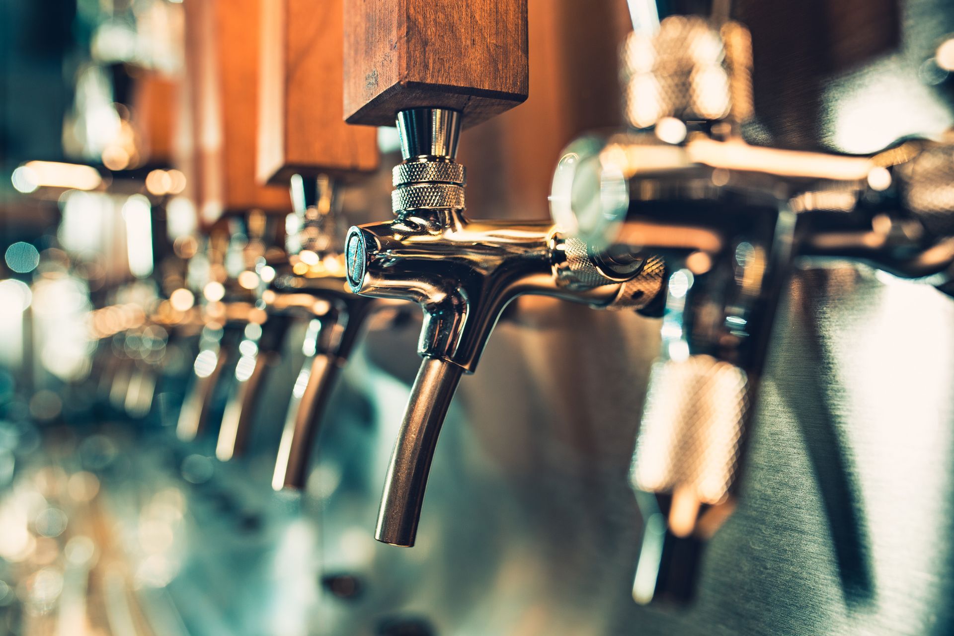 Close-up of beer taps in a bar; chrome and wooden handles.