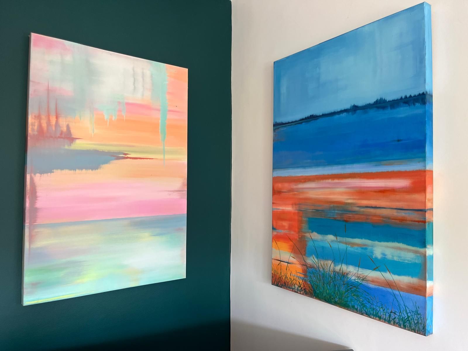 Two colorful abstract paintings on walls; one pink/orange/blue, the other blue/orange/green.