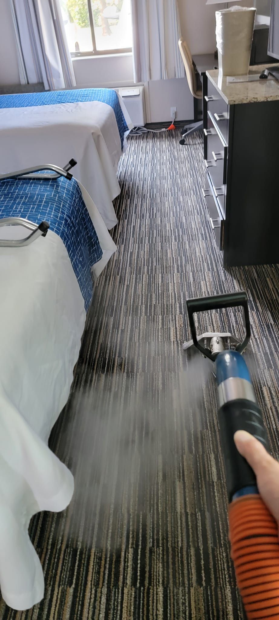 A person is holding a vacuum cleaner in a hotel room.