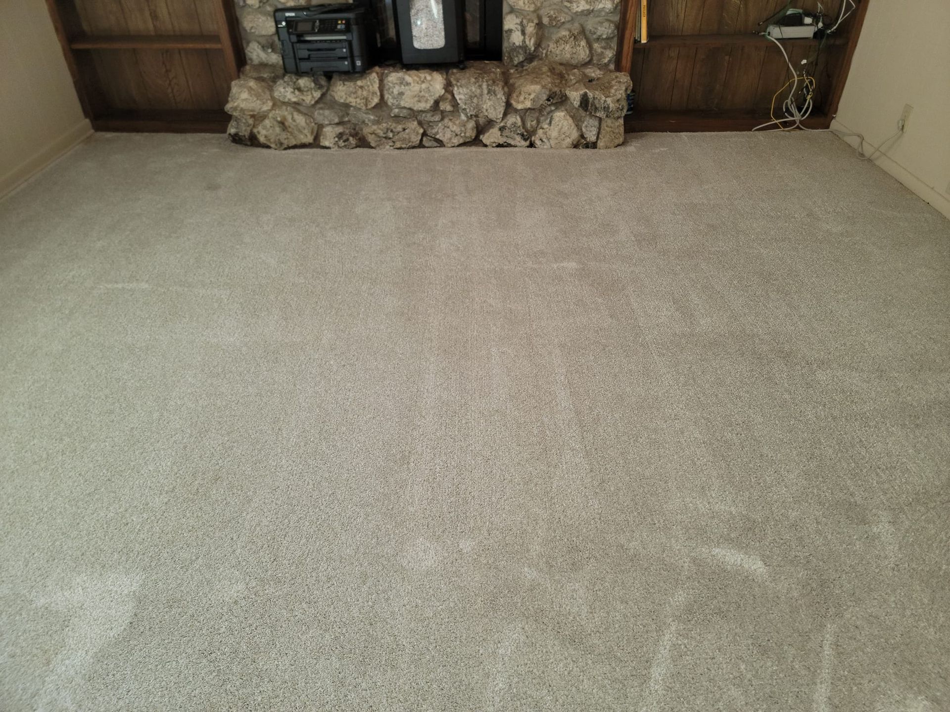 A living room with a fireplace and a carpeted floor