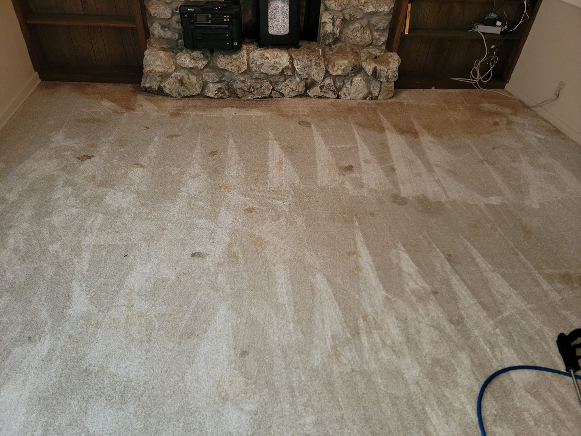 A living room with a fireplace and a dirty carpet.