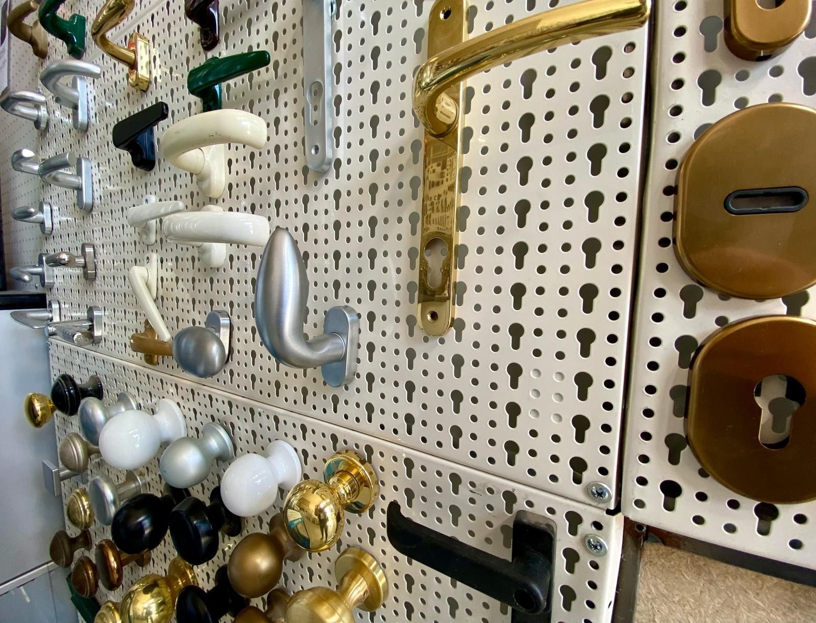 Una parete con molti tipi diversi di maniglie e pomelli per porte