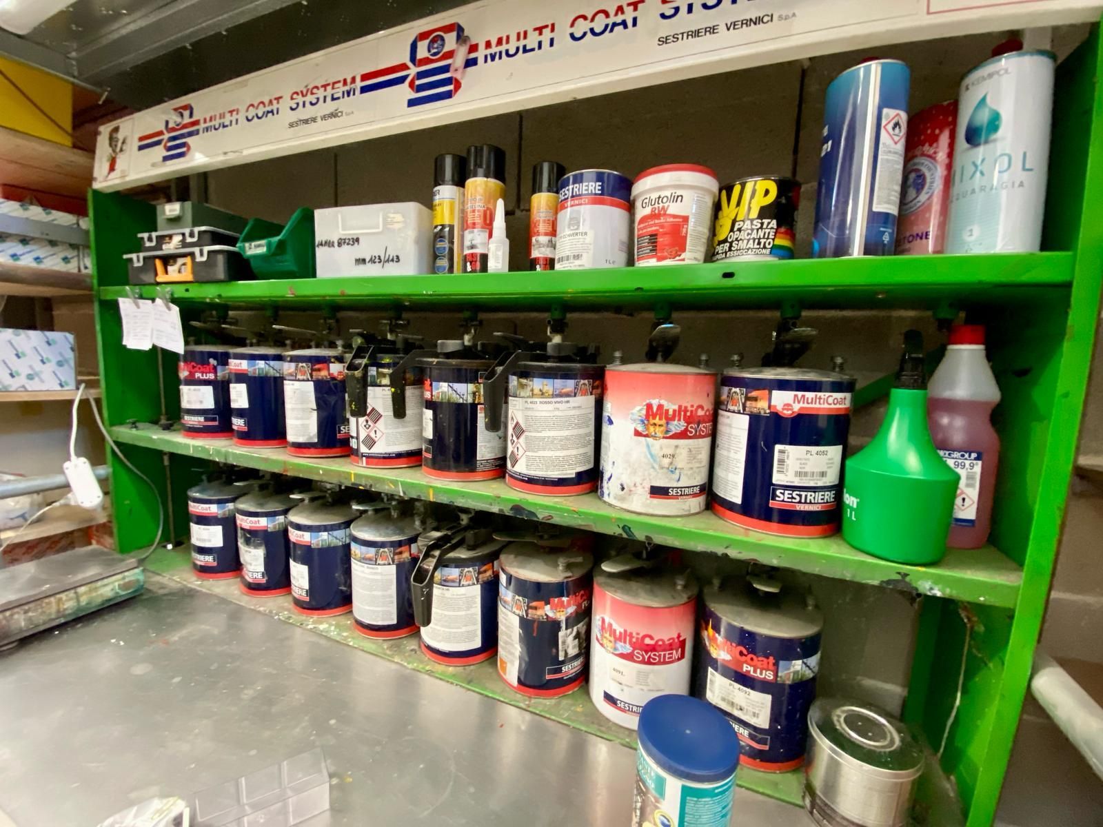 Uno scaffale verde pieno di tanti contenitori di vernice