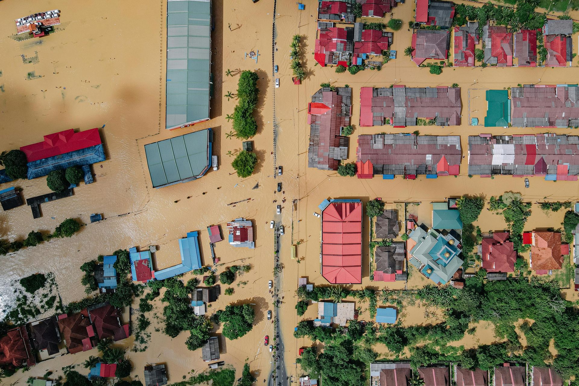 Flooded town from above; brown water surrounds buildings with red and blue roofs.