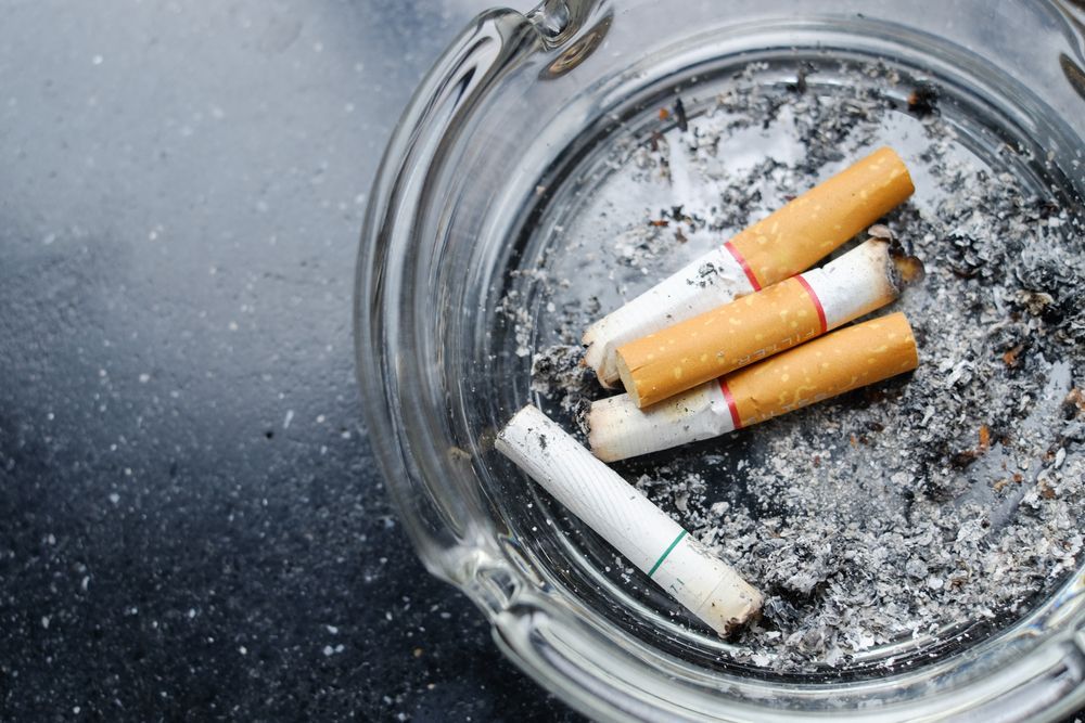 Blue carpet cleaning machine and tools set up on a light-colored carpet next to a white couch.