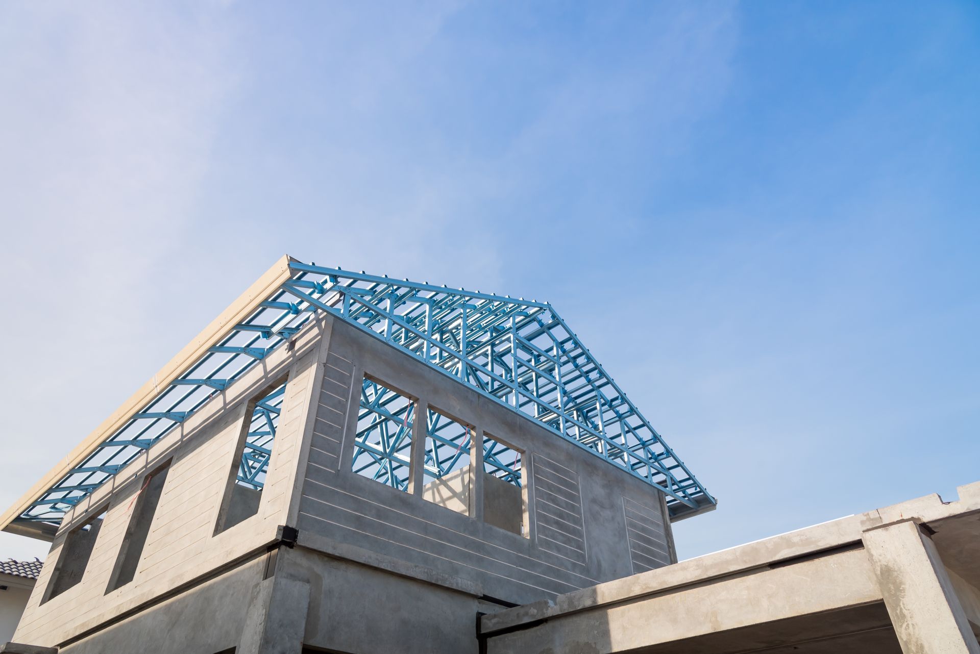 A house is being built with a blue roof and a blue sky in the background.