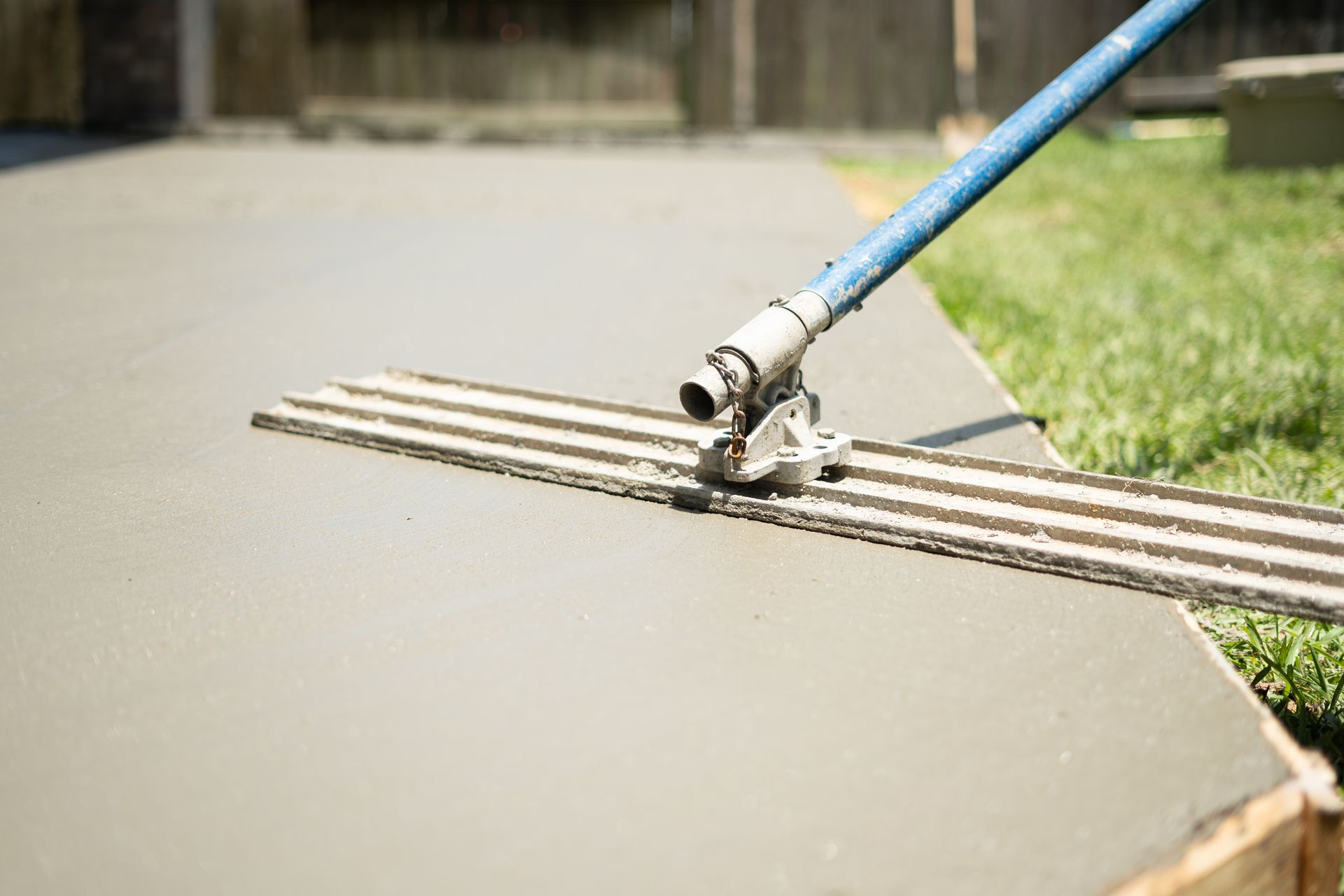 A person is using a trowel to level a concrete driveway.