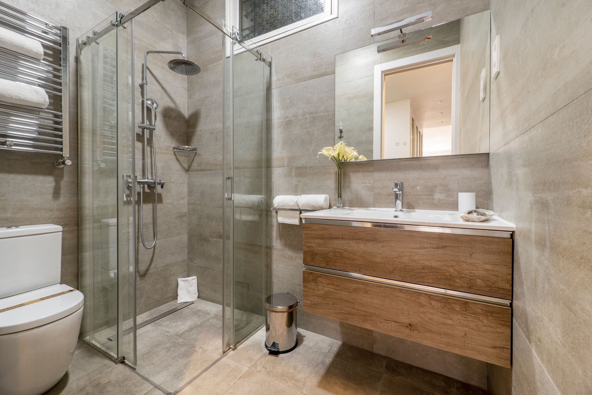 A bathroom with a toilet , sink , shower and mirror.