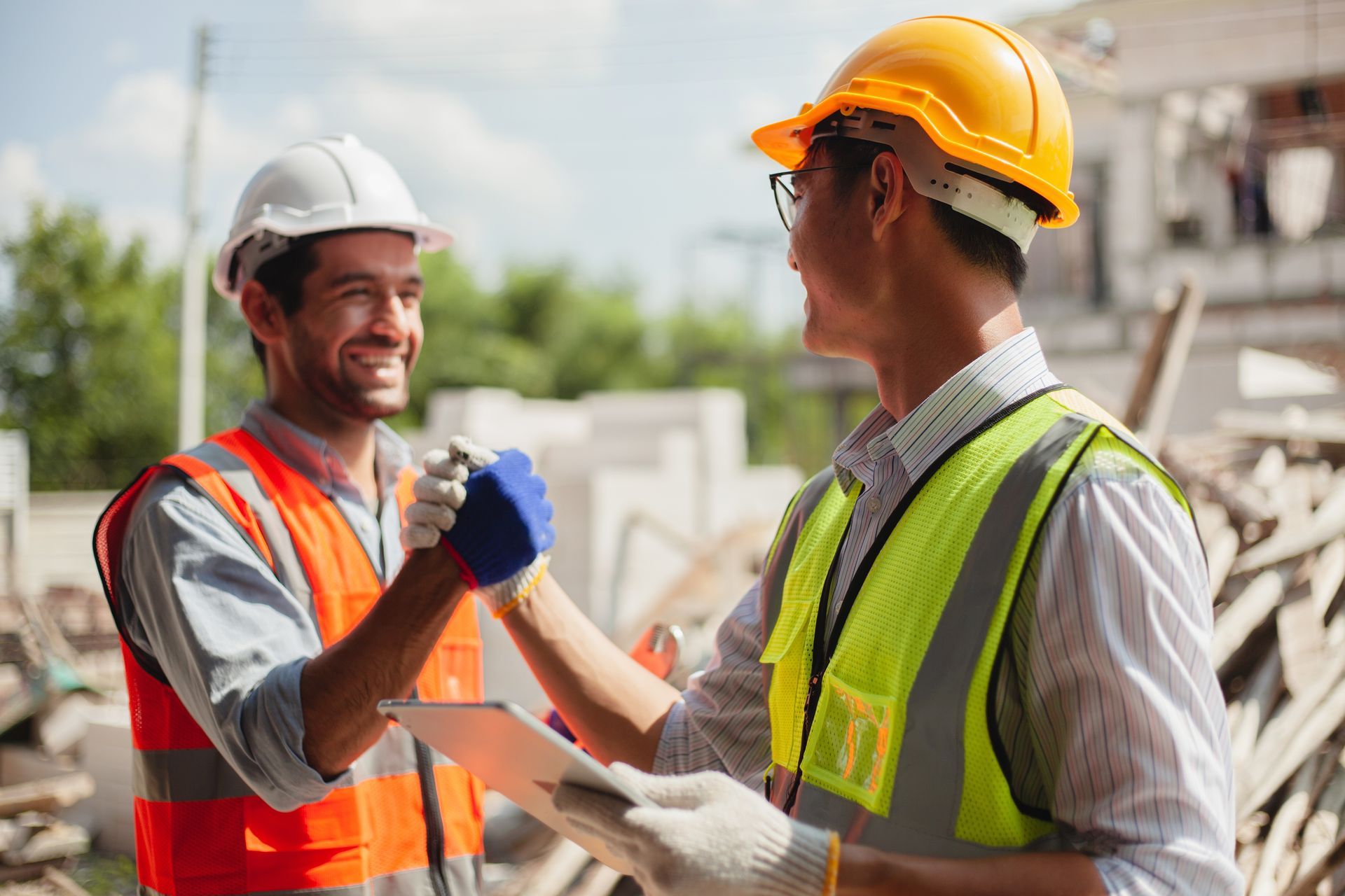 Two construction workers are shaking hands at a construction site.