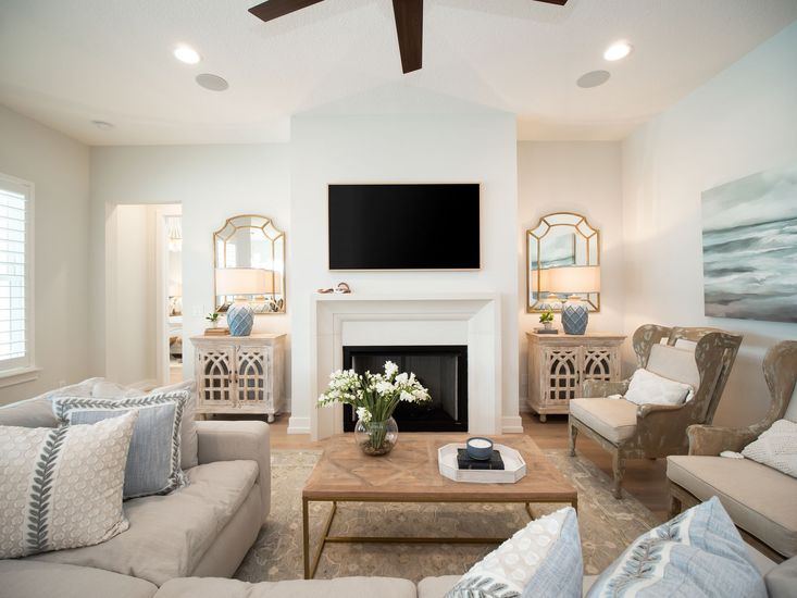 A living room with a fireplace , couch , chairs and a flat screen tv.