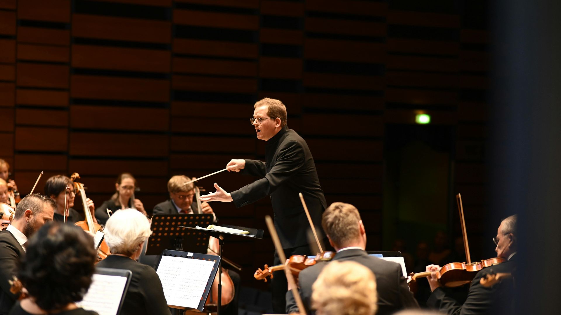 A man is leading an orchestra on a stage.