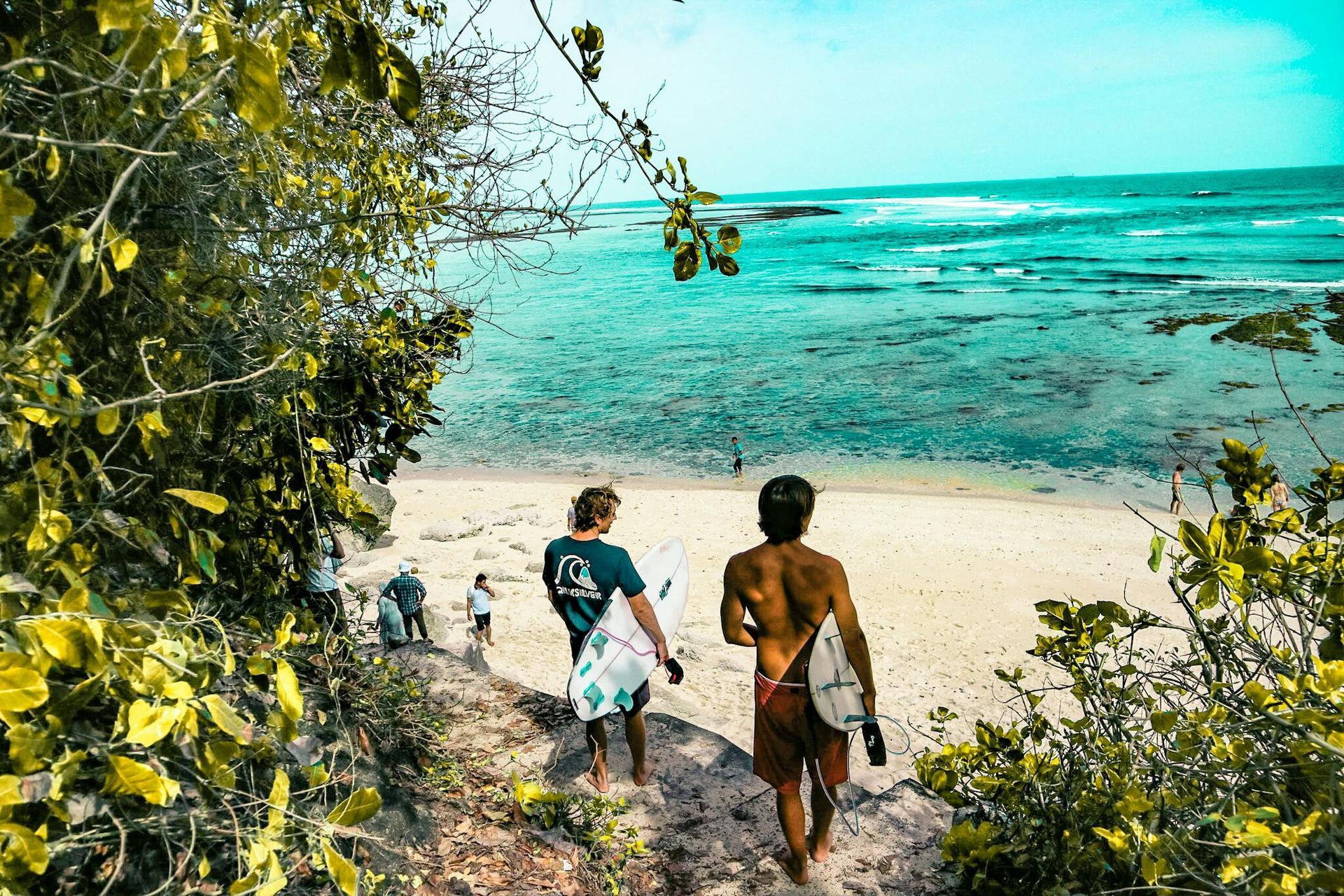 A man and a woman are walking down a path to the beach.