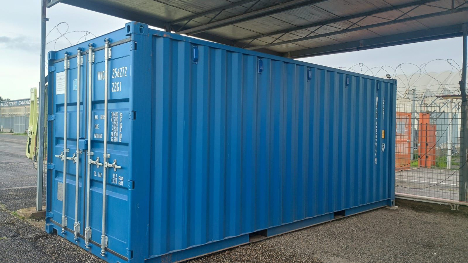 Container blu sotto una tettoia metallica.