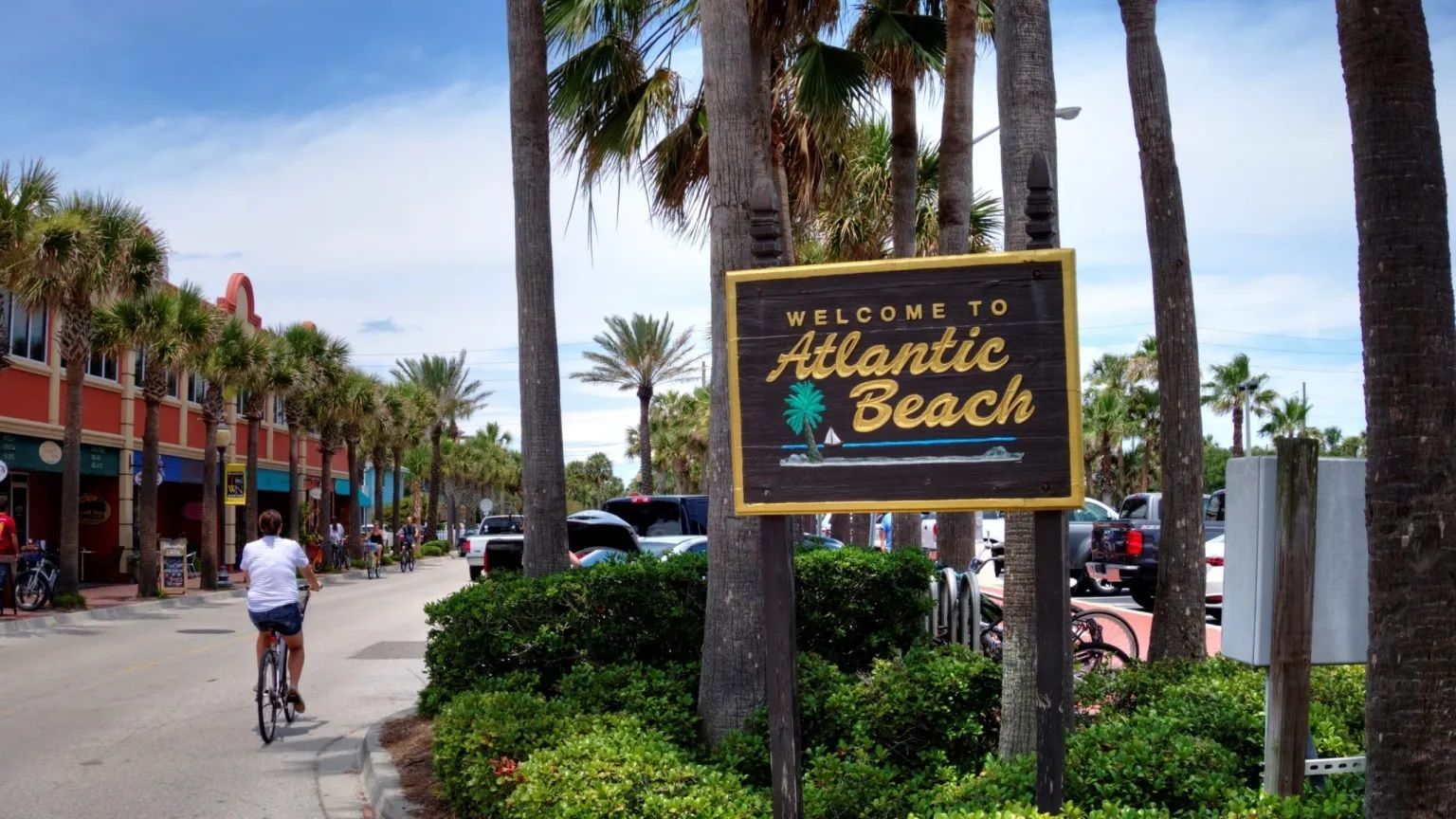Person installing pink fiberglass insulation in a wooden wall frame.