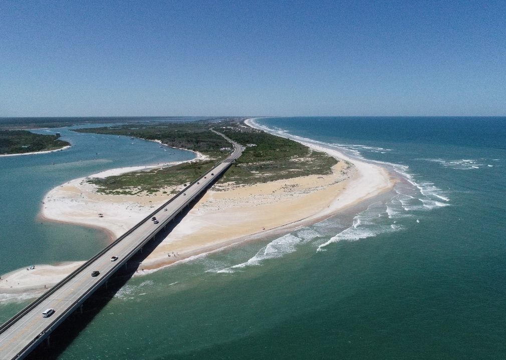 Person installing pink fiberglass insulation in a wooden wall frame.