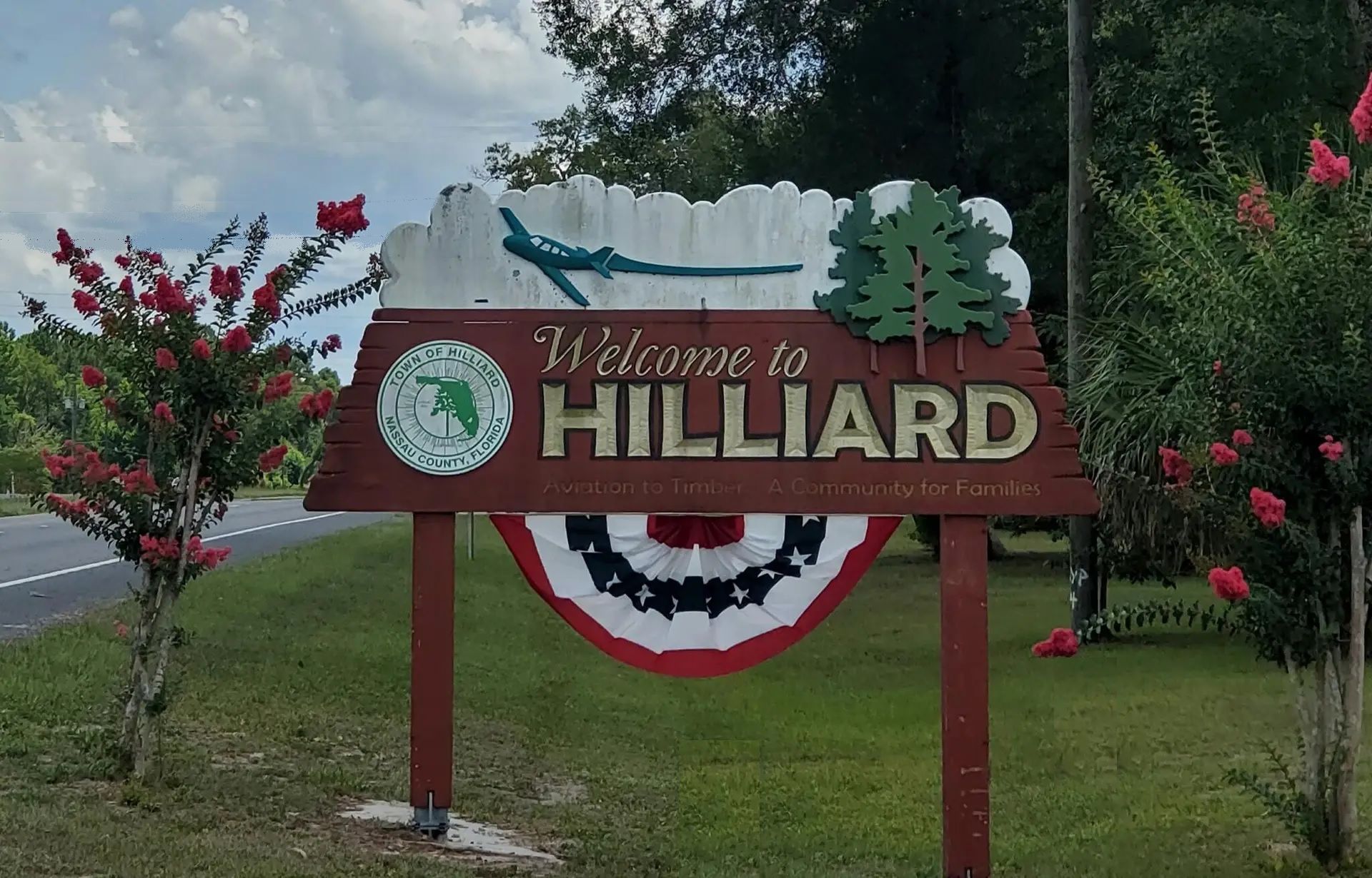 Person installing pink fiberglass insulation in a wooden wall frame.