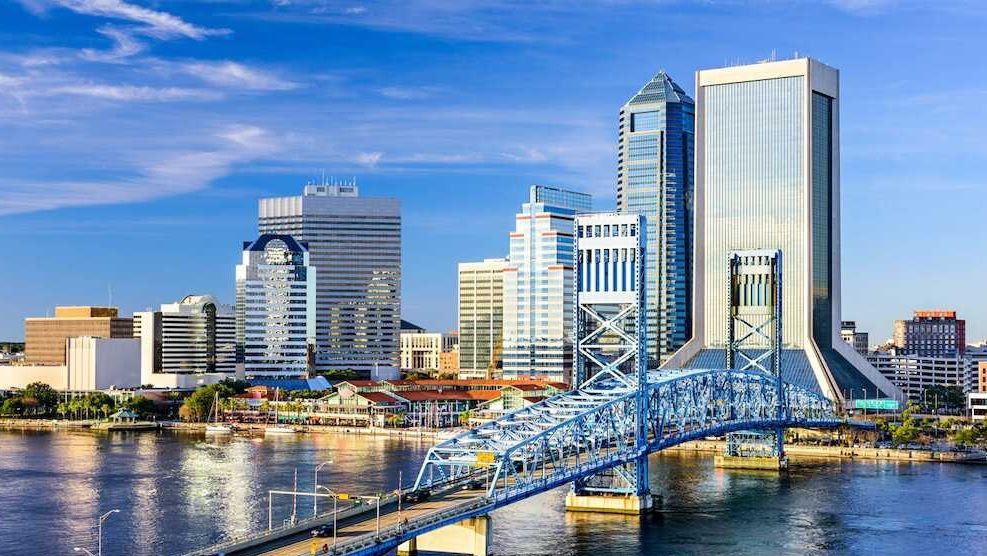 City skyline with blue bridge spanning a river under a clear sky.