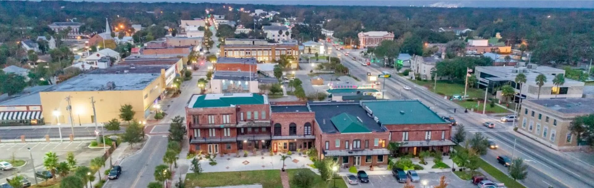 Person installing pink fiberglass insulation in a wooden wall frame.