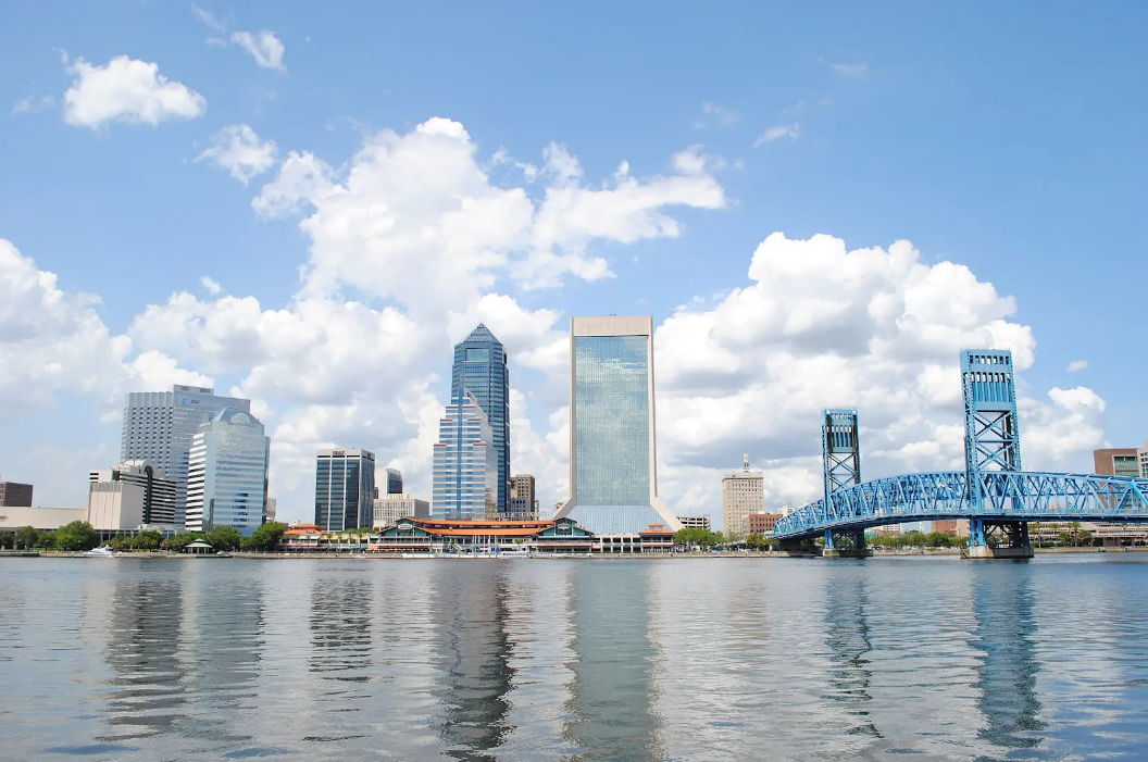 Person installing pink fiberglass insulation in a wooden wall frame.
