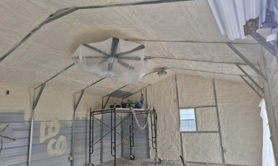 Interior of building, insulated with spray foam, containing scaffolding and a ceiling fan.