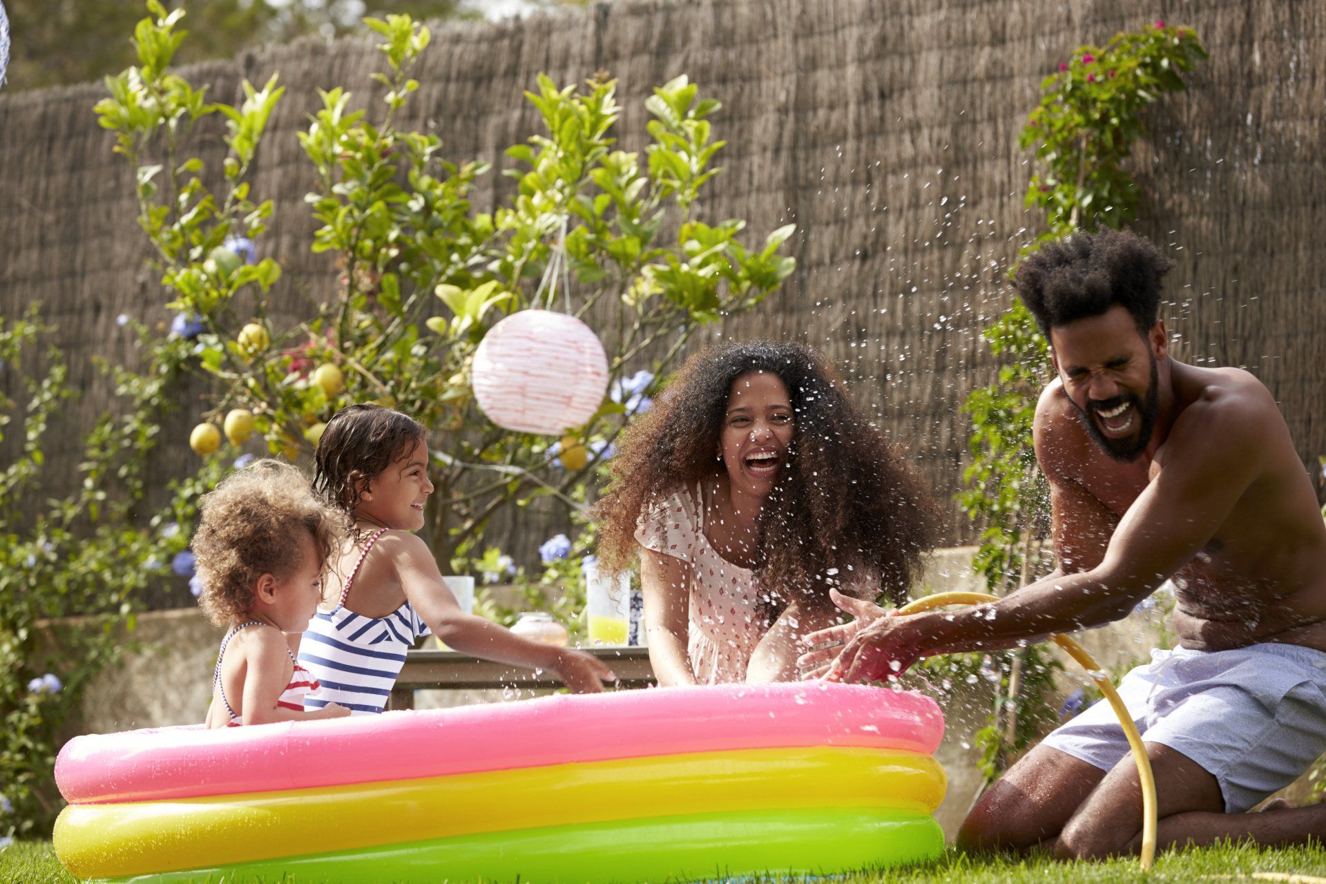 A family is playing in an inflatable pool in their backyard.