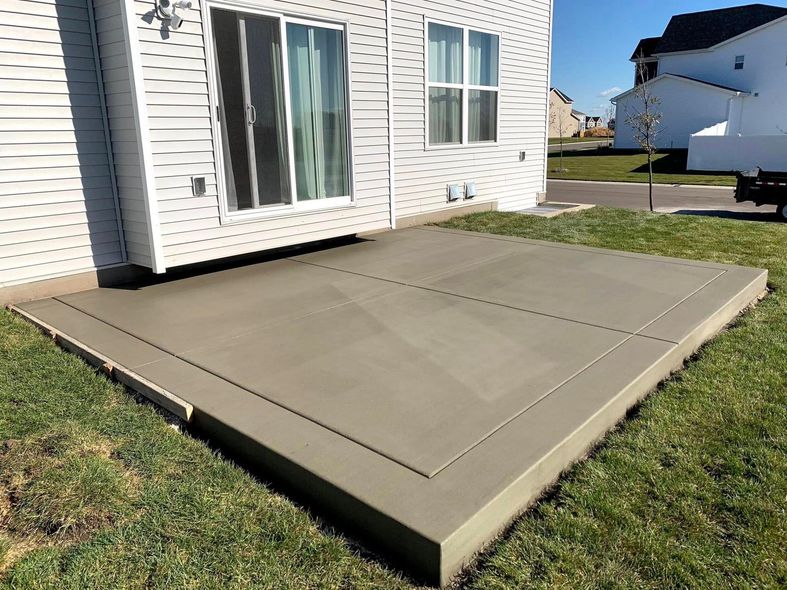 A concrete patio is being built in front of a house.