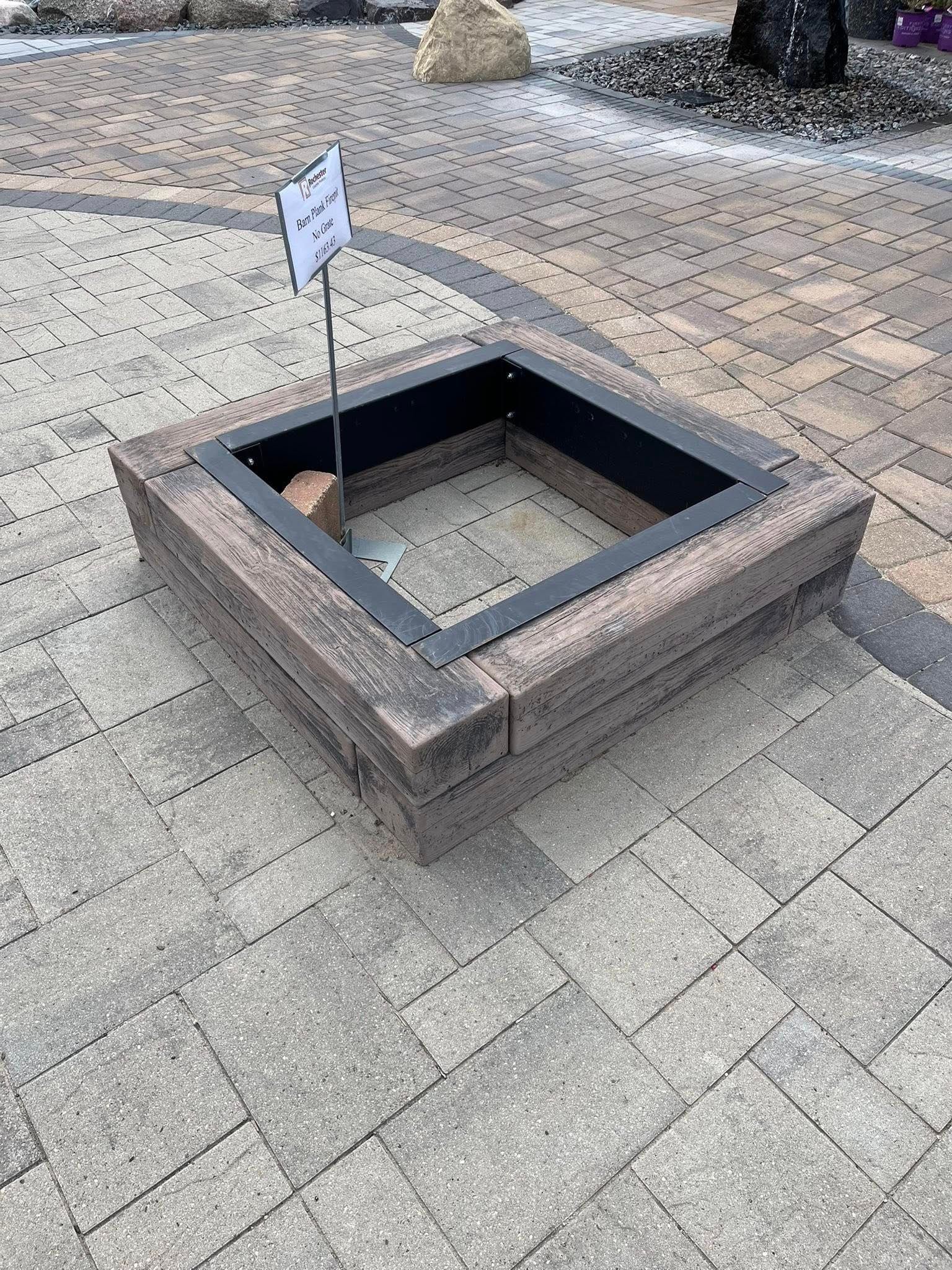 A wooden fire pit is sitting on top of a brick patio.