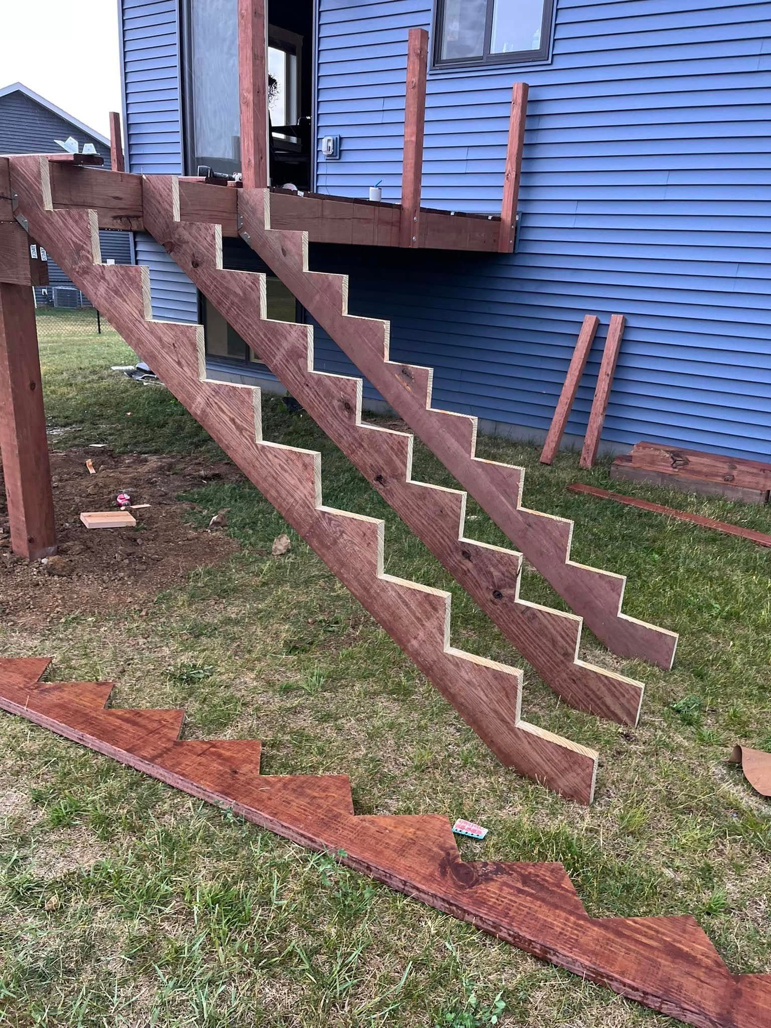 A wooden staircase is being built in front of a blue house.