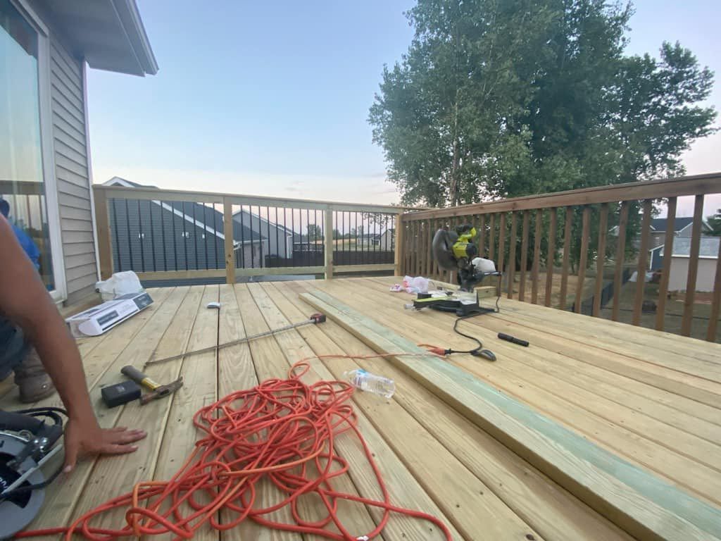 A person is working on a wooden deck with tools.